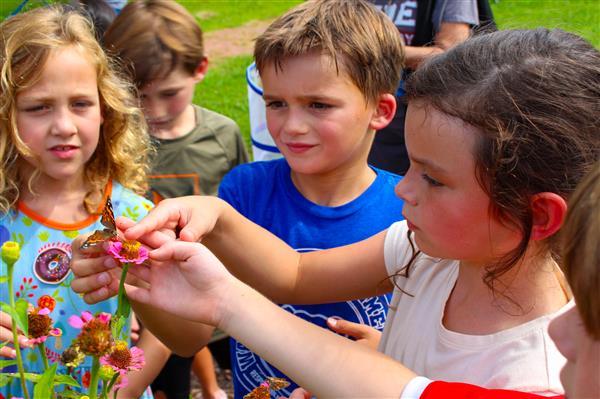 students in a flower garden with butterflies